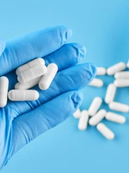 врач держит капсулы антибиотиков в руке